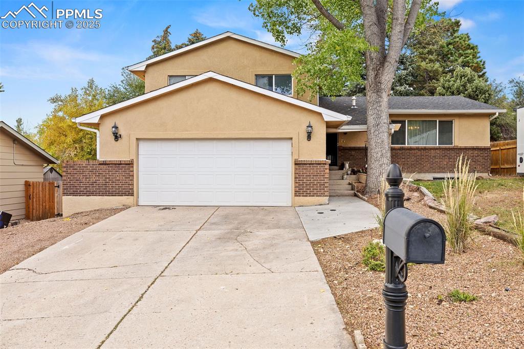 Caption: Traditional home with concrete driveway, stucco siding, brick siding, an attached garage, and a pati
