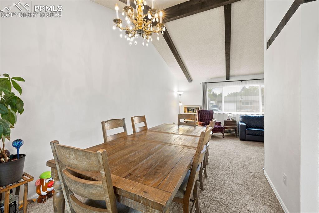 Image 13 of 50: Carpeted dining area featuring a chandelier