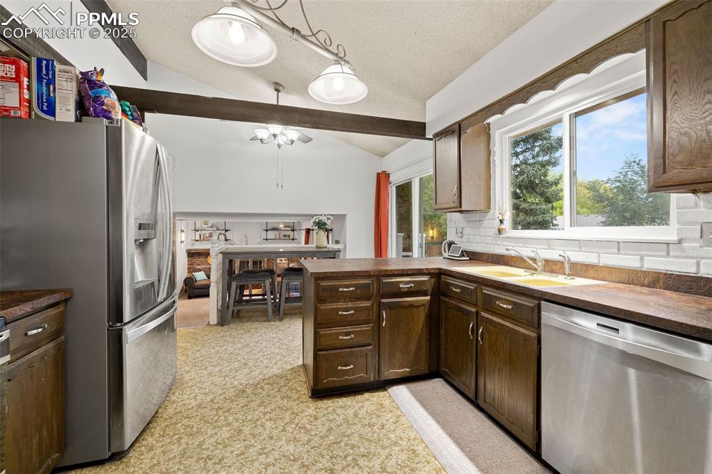 Image 14 of 50: Kitchen with a peninsula, stainless steel appliances, dark countertops, dec