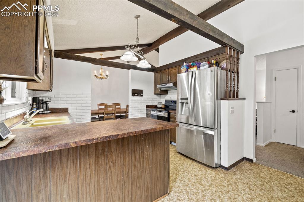 Image 16 of 50: Kitchen with tasteful backsplash, stainless steel appliances, dark countert