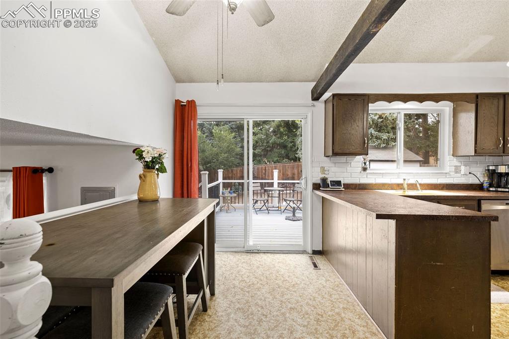 Image 17 of 50: Kitchen with a textured ceiling, dark countertops, decorative backsplash, h