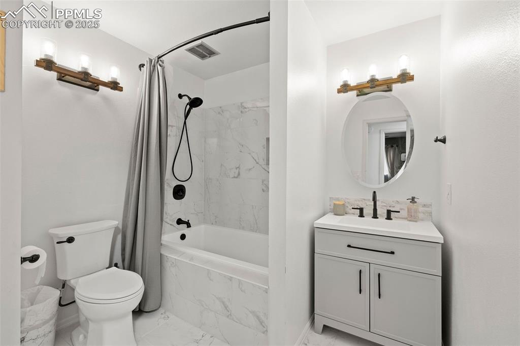Image 20 of 50: Full bath featuring a combined bath / shower with marble appearance, vanity