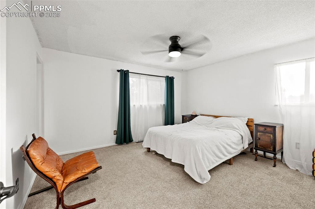 Image 22 of 50: Bedroom with carpet, ceiling fan, and a textured ceiling