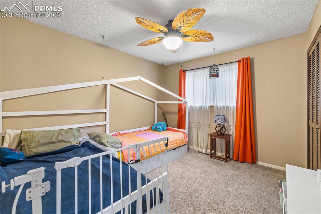 Image 24 of 50: Carpeted bedroom featuring a textured ceiling, a ceiling fan, and a closet