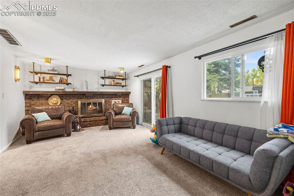 Image 25 of 50: Living area with carpet flooring, plenty of natural light, a fireplace, and