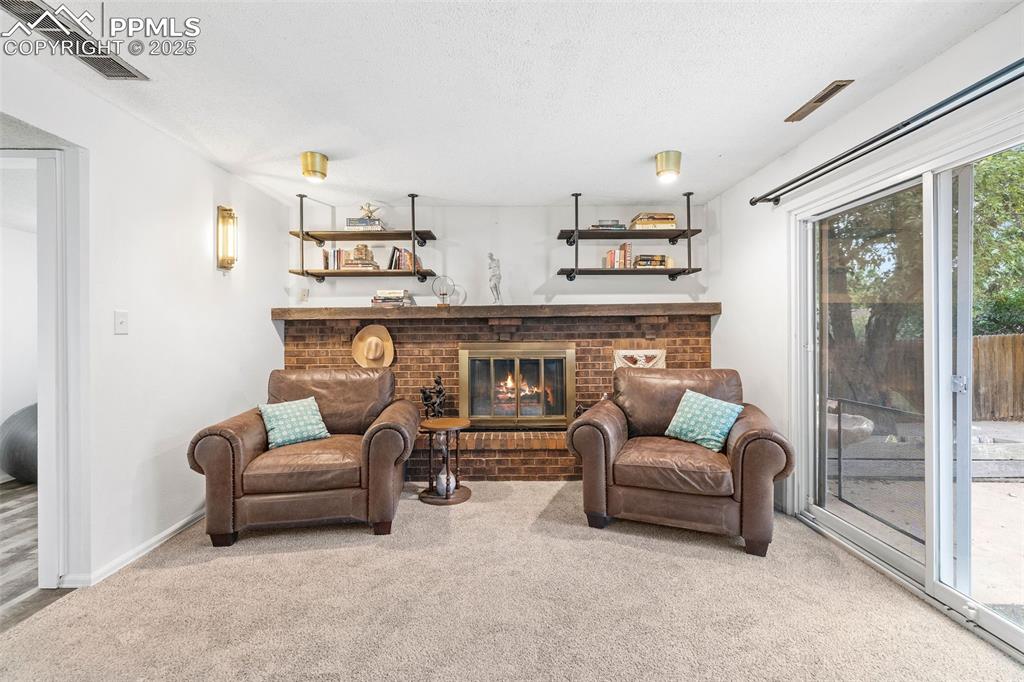 Image 27 of 50: Living room featuring a fireplace, carpet, and a textured ceiling