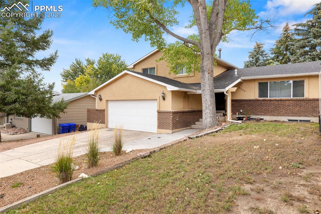 Image 3 of 50: View of front facade with brick siding, driveway, stucco siding, and a fron