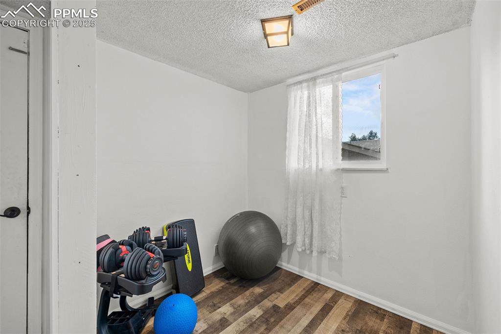 Image 31 of 50: Workout area with dark wood-type flooring and a textured ceiling