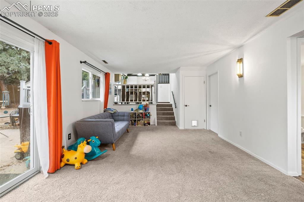 Image 32 of 50: Living room with carpet flooring, a textured ceiling, and stairway