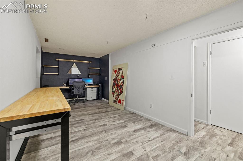 Image 36 of 50: Office area with wine cooler, light wood finished floors, and a textured ce