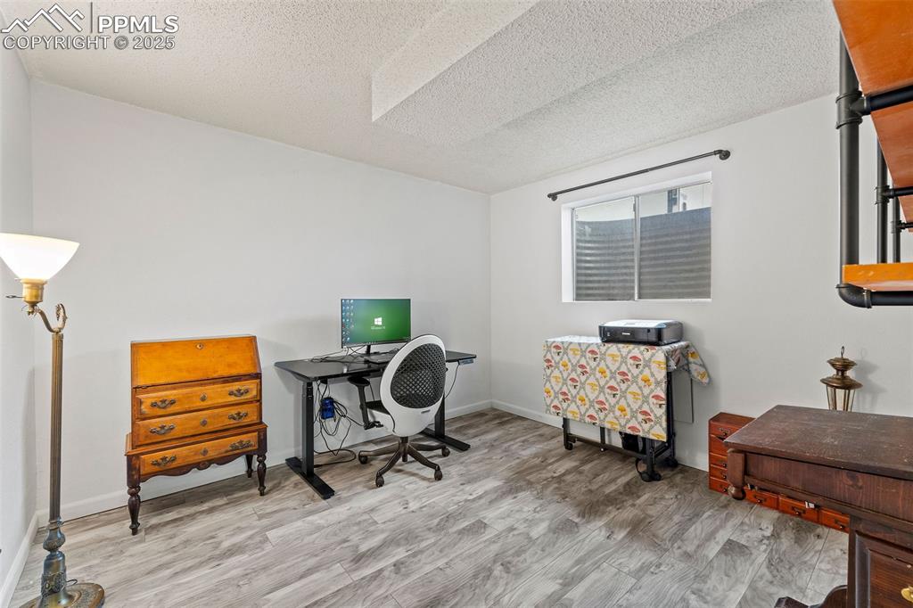 Image 38 of 50: Office with a textured ceiling and light wood-type flooring