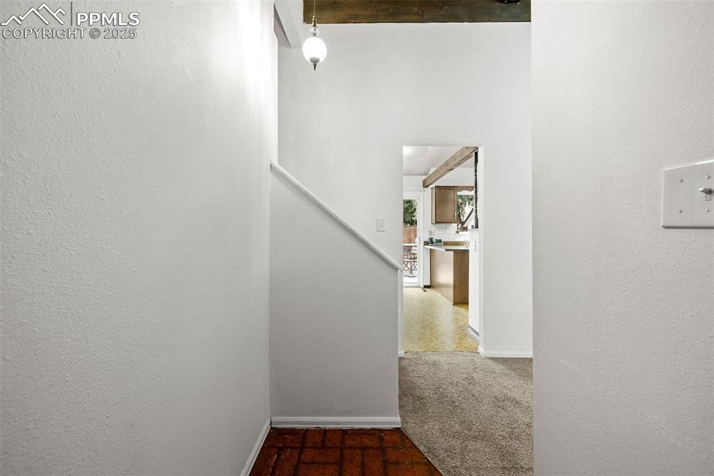 Image 7 of 50: Corridor featuring beamed ceiling, a textured wall, and dark carpet