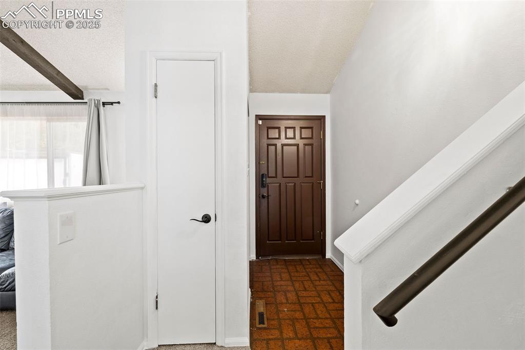 Image 8 of 50: Entrance foyer featuring a textured ceiling, brick patterned floors, and be