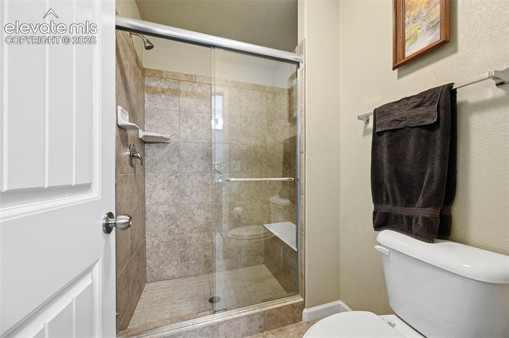 Image 10 of 38: Shower enclosure featuring a built-in bench, tiled walls, and a glass slidi