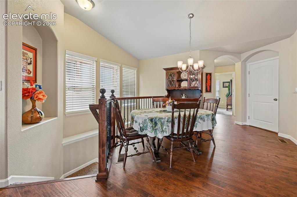 Image 15 of 38: Dining area featuring vinyl flooring, an arched doorway, and a chandelier