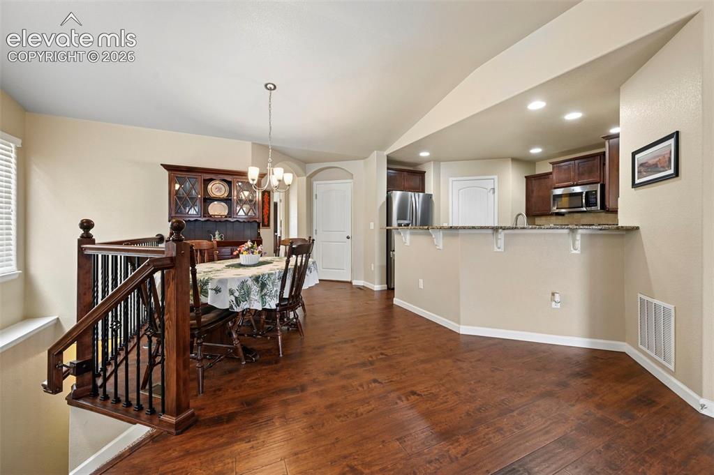 Image 16 of 38: Open-concept living space vinyl flooring, kitchen with dark wood cabinetry