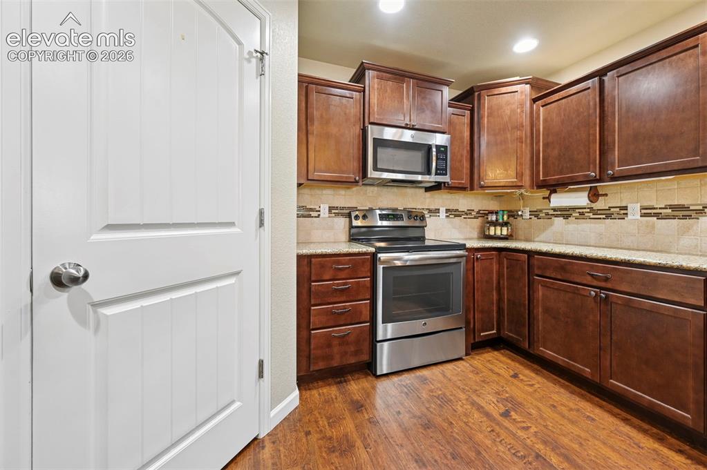 Image 18 of 38: Kitchen featuring vinyl flooring, dark wood cabinetry, light-toned countert