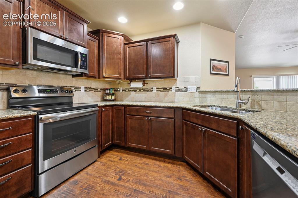 Image 19 of 38: Kitchen featuring dark wood cabinetry, under cabinet lighting and stainless