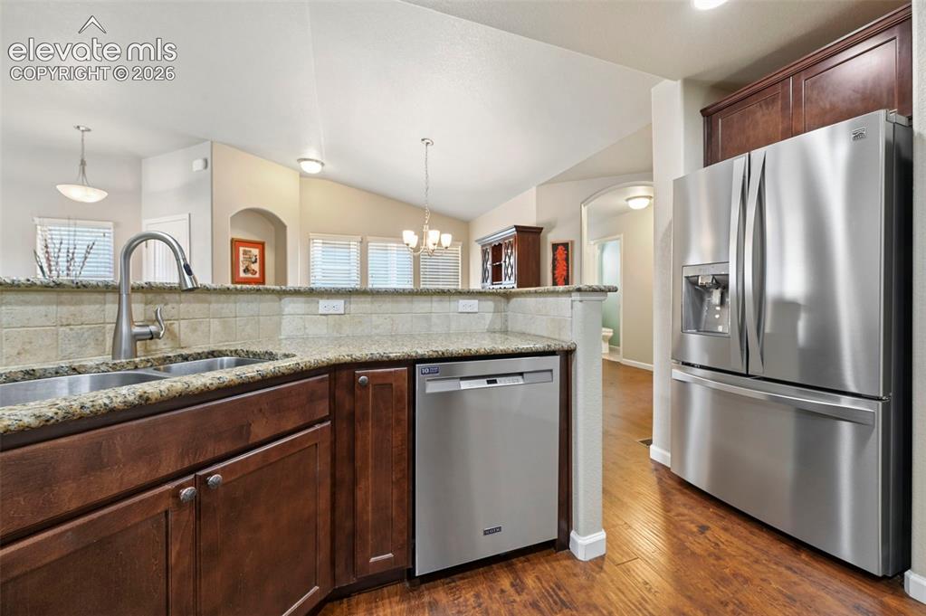 Image 20 of 38: Kitchen featuring stainless steel appliances,dark wood cabinetry, a double