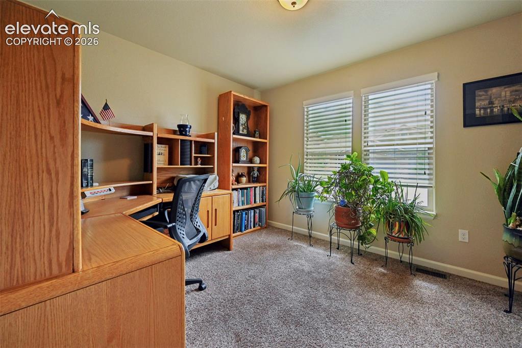 Image 21 of 38: Office featuring two windows with horizontal blinds, neutral wall paint, an
