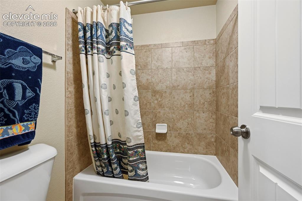 Image 33 of 38: Baement Bath with Full-sized bathtub with tiled surround featuring a neutra