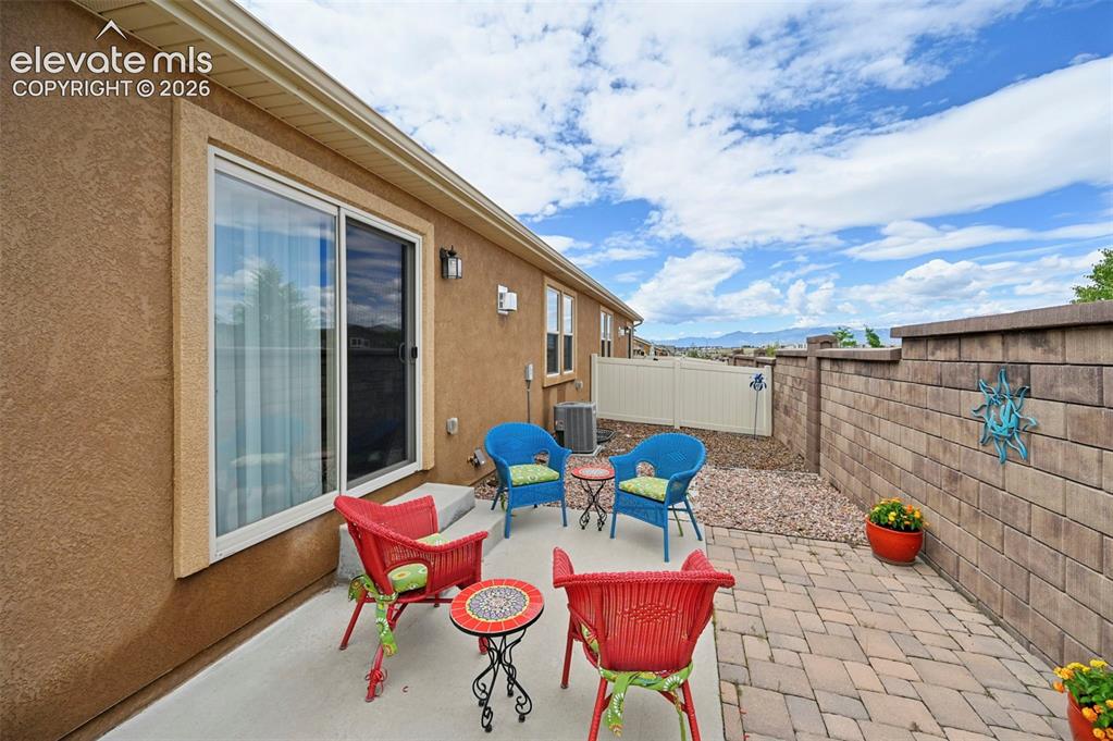 Image 38 of 38: Paved patio area featuring a block retaining wall, a sliding glass door, an