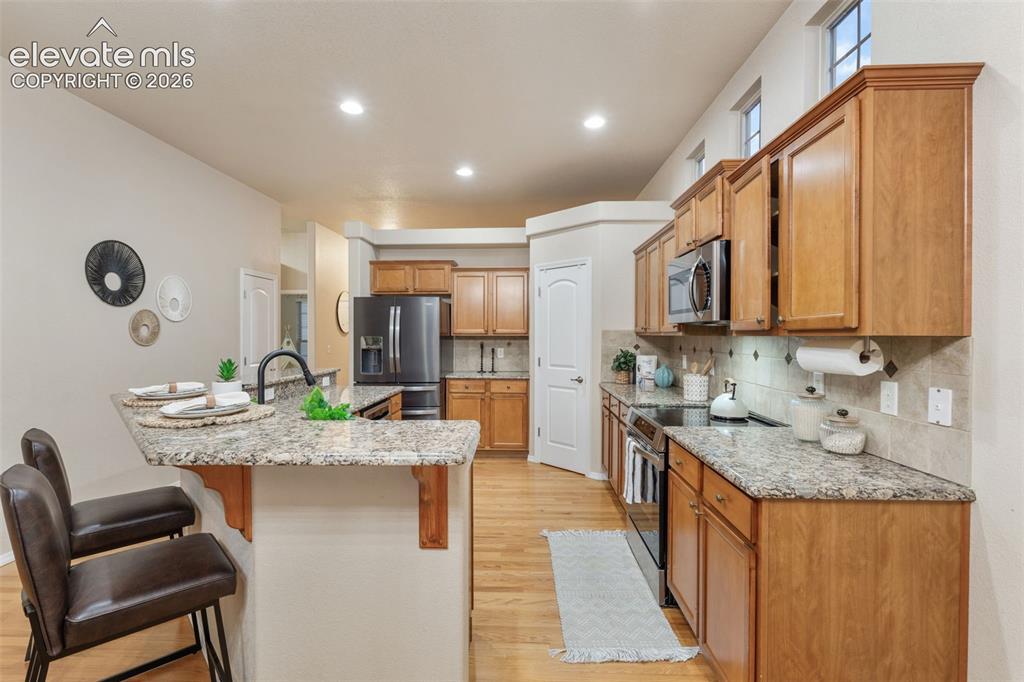 Image 10 of 50: Kitchen featuring wood-finish flooring, granite countertops, wood cabinetry