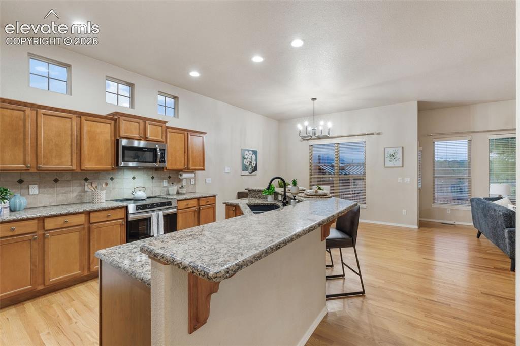 Image 12 of 50: Kitchen featuring wood cabinetry, stainless steel appliances, granite count