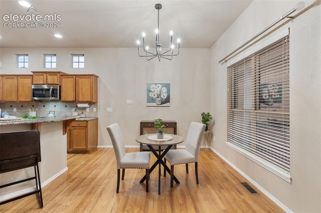 Image 13 of 50: Wood-finish flooring throughout, with a contemporary chandelier, a large wi