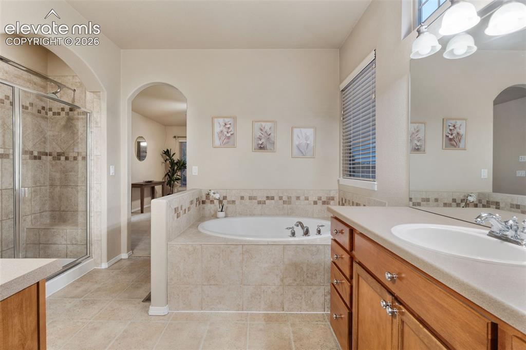 Image 20 of 50: Tiled walk-in shower with glass enclosure, built-in soaking tub with tiled