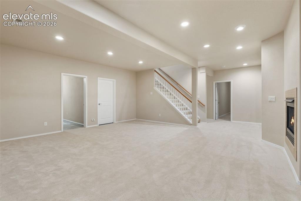 Image 24 of 50: Spacious carpeted room featuring recessed lighting, a built-in fireplace, a