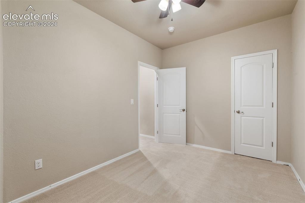 Image 28 of 50: Neutral wall paint, light-toned carpeting, white trim, and a ceiling fan