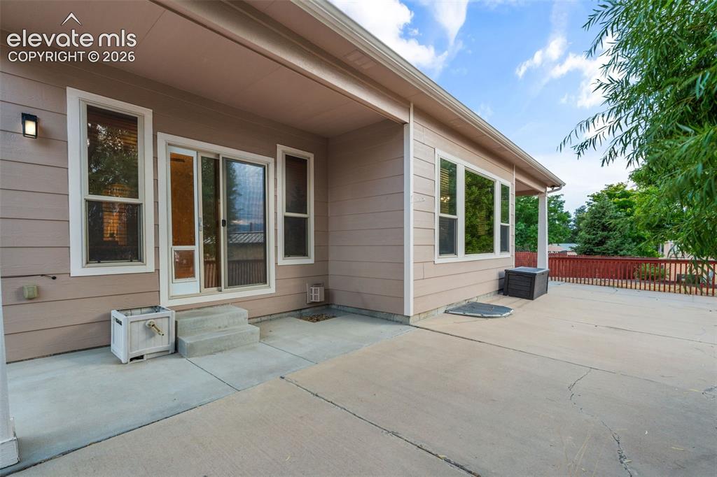Image 39 of 50: Expansive concrete patio with a covered outdoor area, sliding glass door ac