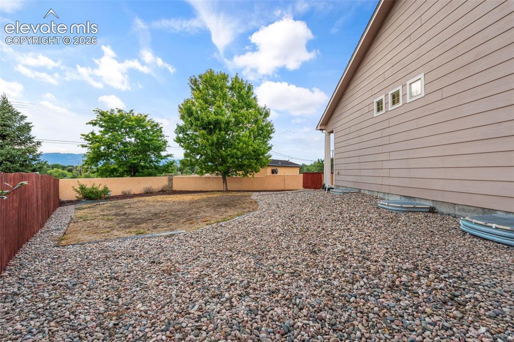 Image 40 of 50: Exterior siding with multiple small windows, pea gravel landscaping, wood f