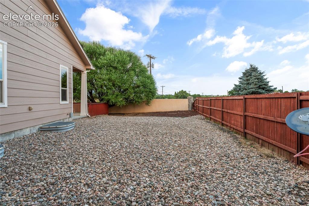 Image 42 of 50: Siding exterior with multiple windows, leading to a gravel yard with a stai