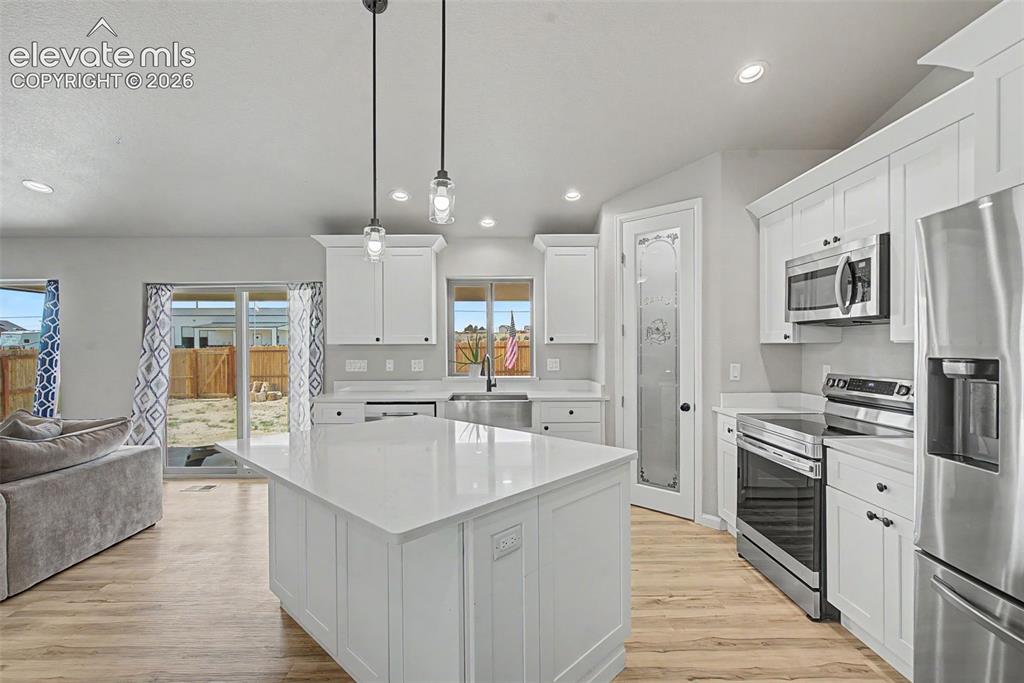 Image 12 of 47: Modern kitchen featuring a large central island with a solid surface counte