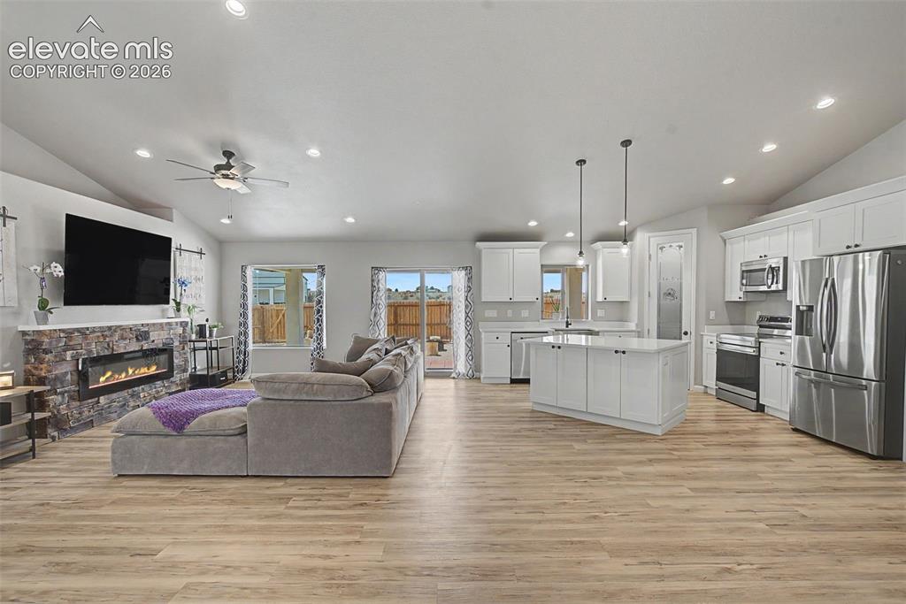 Image 13 of 47: Open-concept living space featuring wood-finish flooring, a stone-faced fir