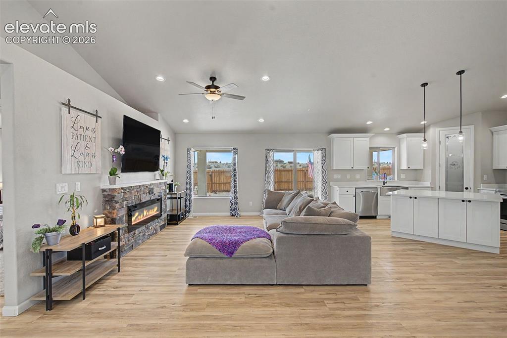 Image 14 of 47: Open-concept living area with wood-finish flooring, vaulted ceilings, and r
