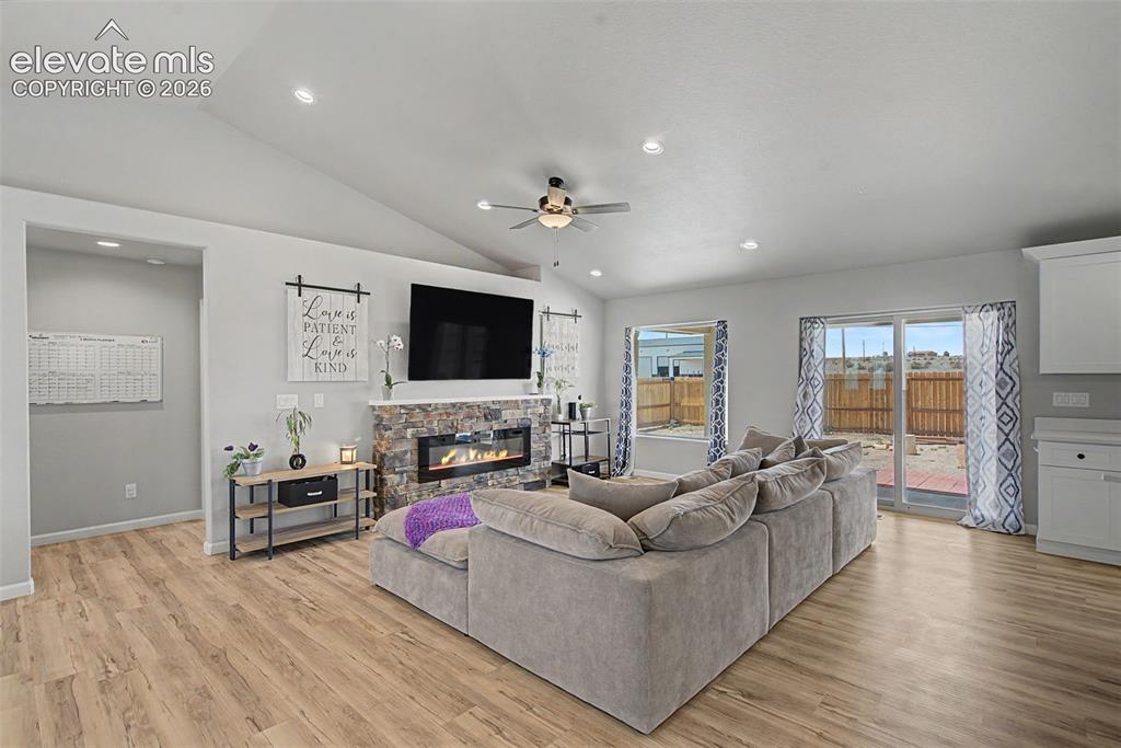 Image 16 of 47: Spacious living area featuring wood-finish flooring, vaulted ceilings with 