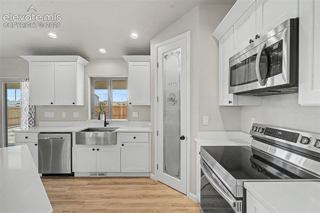 Image 18 of 47: Modern kitchen featuring white shaker cabinetry and stainless steel applian
