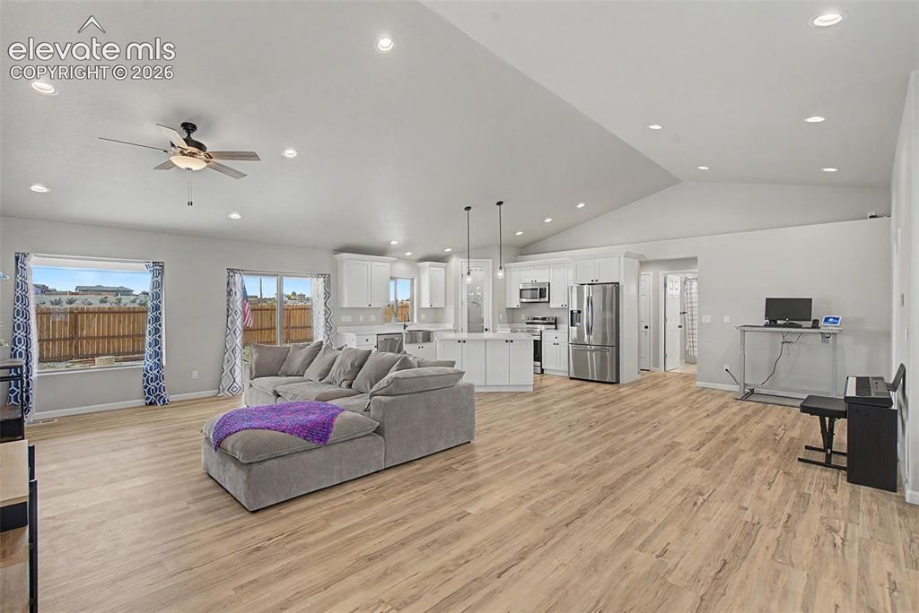 Image 23 of 47: Open-concept living space featuring wood-finish flooring, vaulted ceilings,