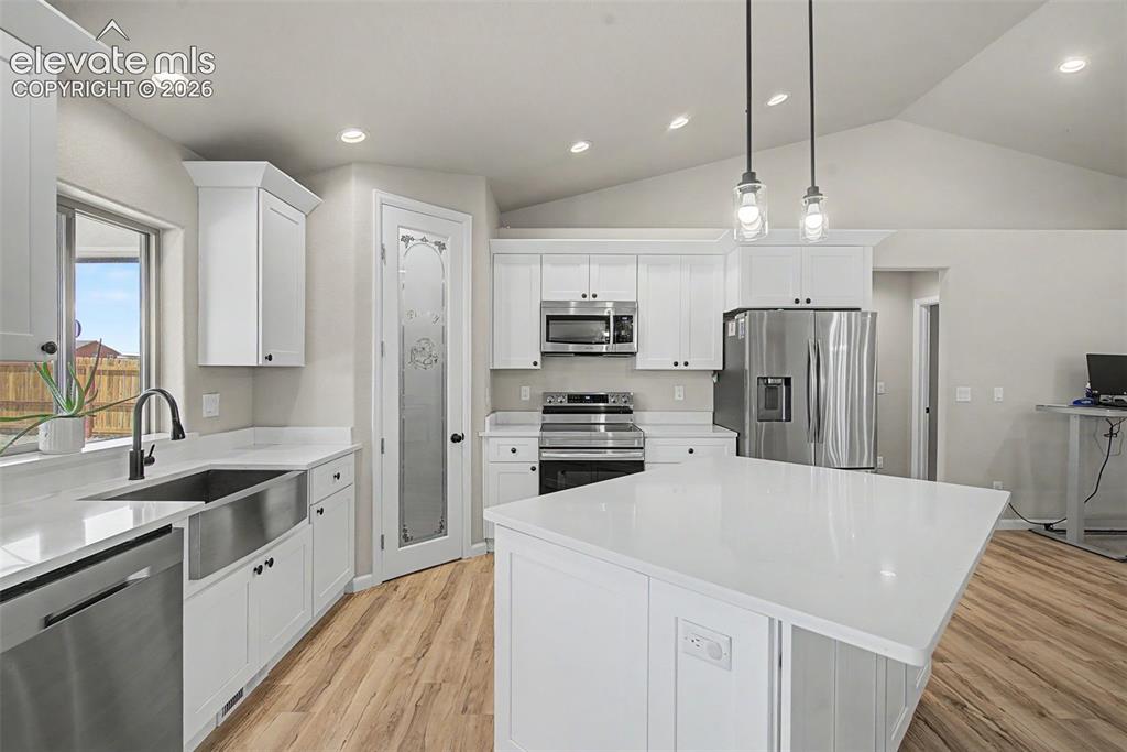 Image 28 of 47: Bright kitchen featuring a substantial island with a white countertop, whit