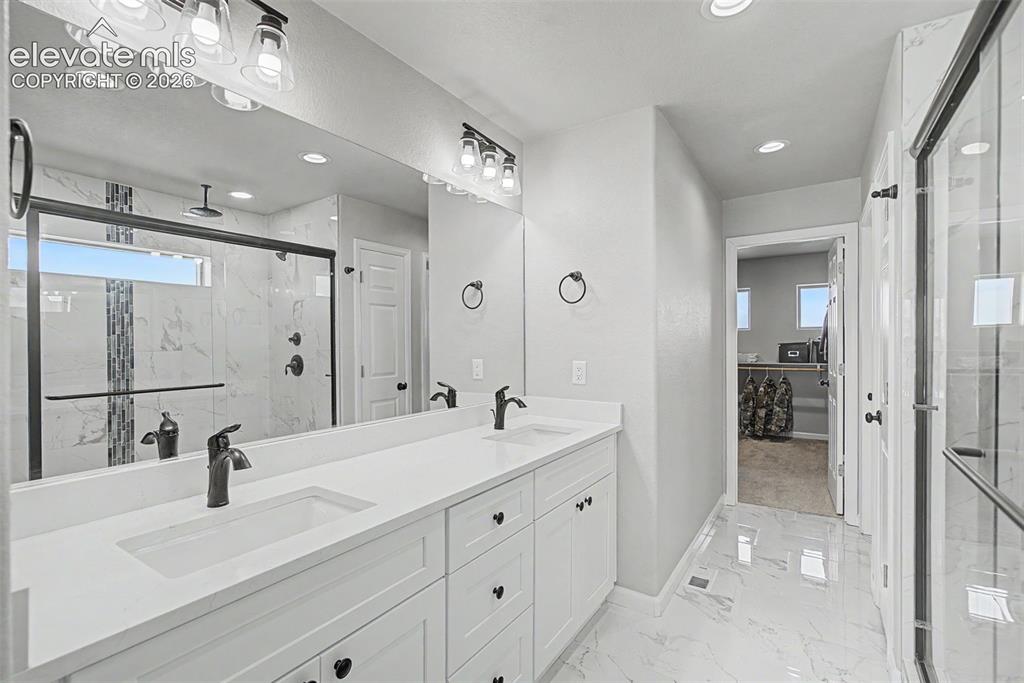 Image 33 of 47: Spacious bathroom featuring a double vanity with white cabinetry, matte bla