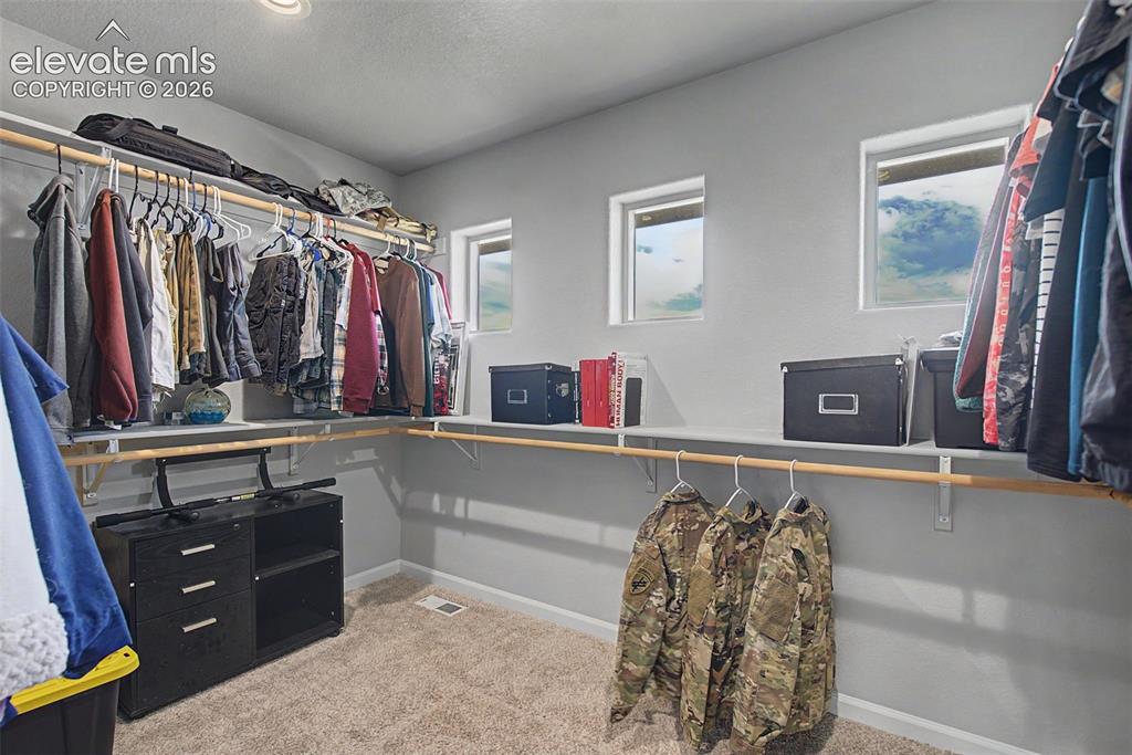 Image 34 of 47: Walk-in closet featuring built-in shelving, multiple hanging rods, recessed