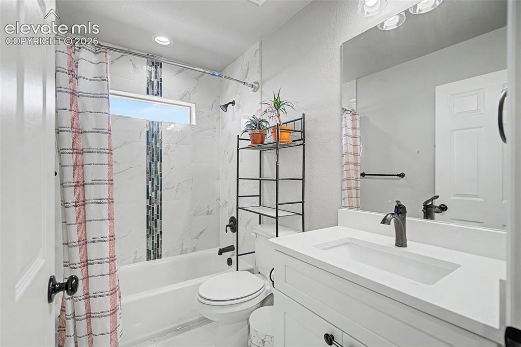 Image 39 of 47: Bathroom featuring white vanity with integrated sink, rectangular mirror, a