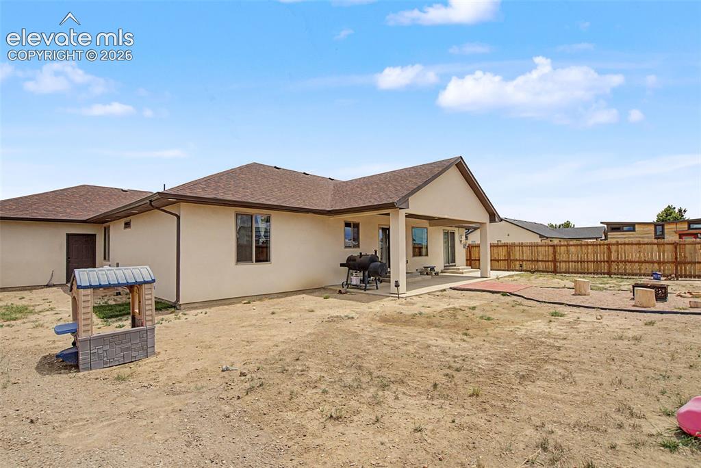 Image 45 of 47: Spacious backyard featuring a covered patio, sliding glass doors, a wood fe