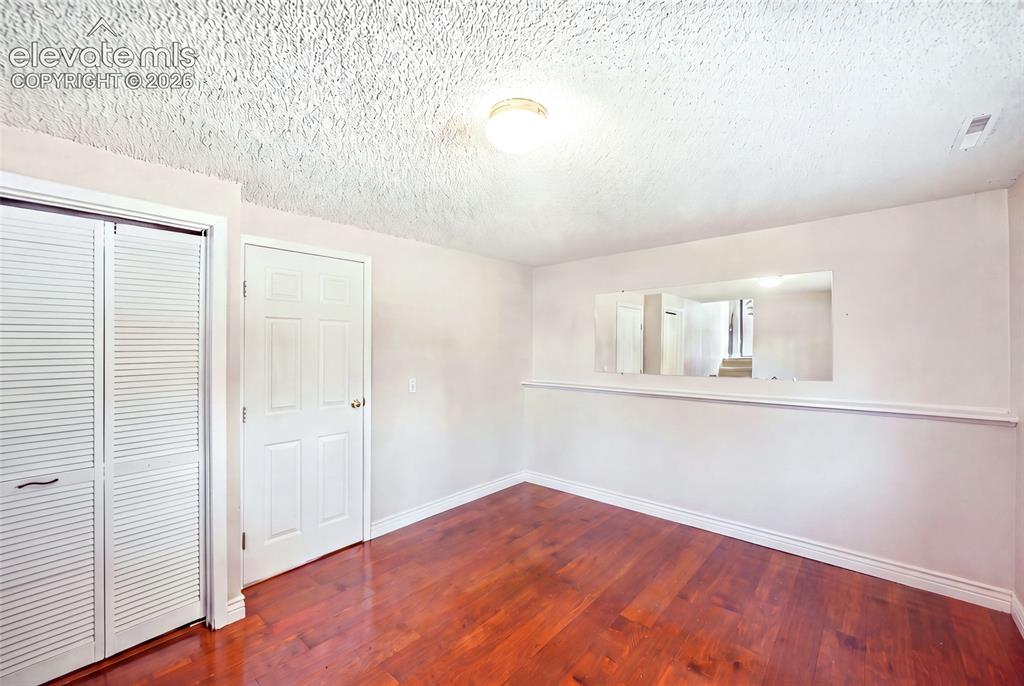 Image 27 of 39: Lower level bedroom with wood flooring.  AI removed items from bedroom