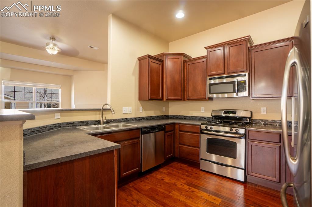 Image 11 of 33: Kitchen with stainless steel appliances, a peninsula, dark wood-style floor