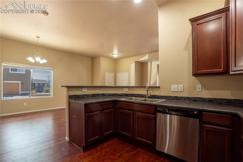 Image 13 of 33: Kitchen featuring dishwasher, a peninsula, dark wood finished floors, and a