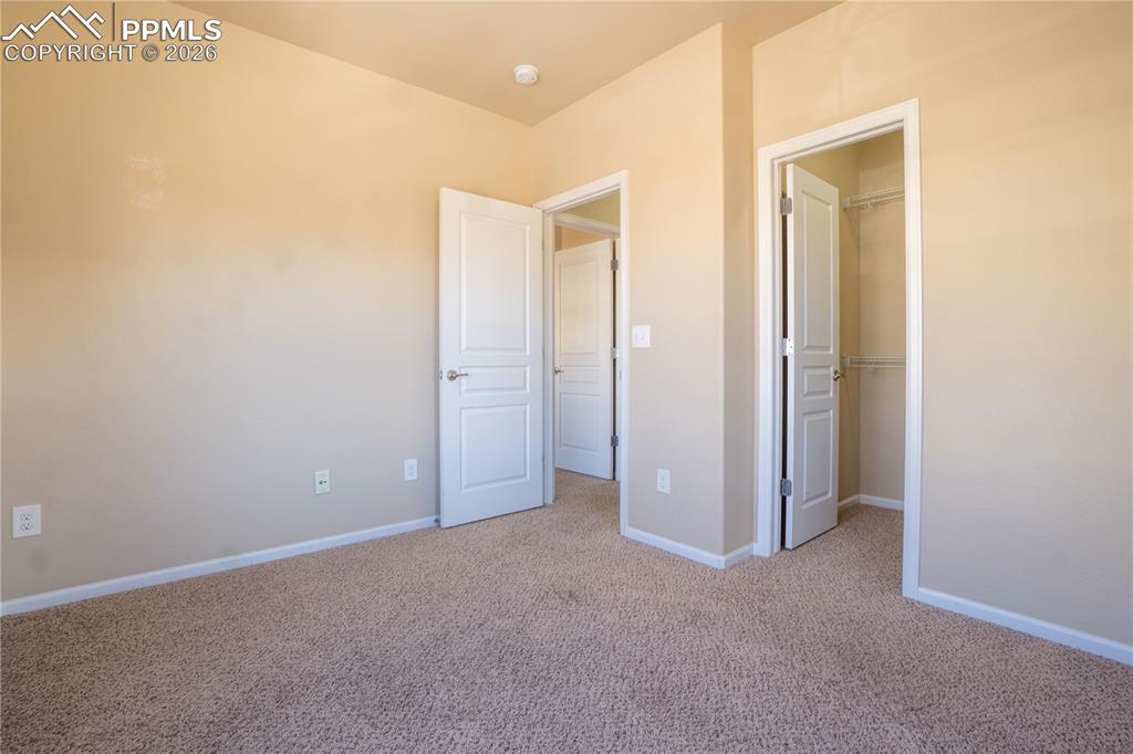 Image 21 of 33: Unfurnished bedroom with a walk in closet and light colored carpet